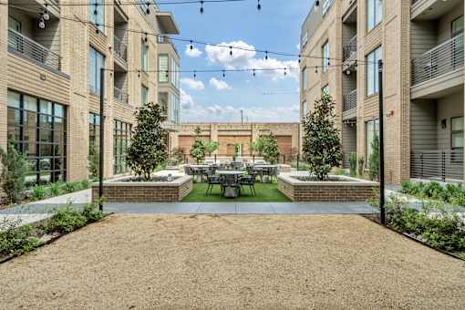 A courtyard surrounded by buildings with a table and chairs in the middle.