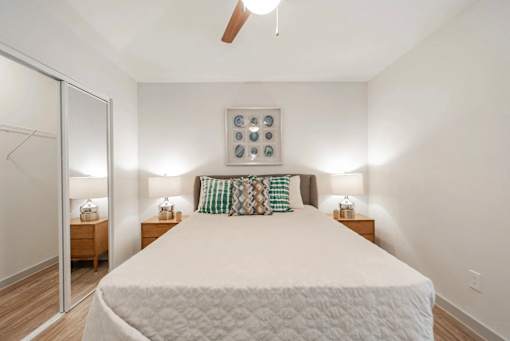 A bedroom with a large bed and two nightstands with lamps.