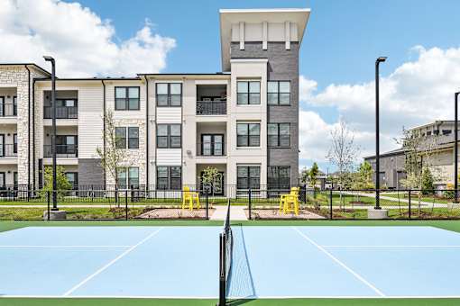 A tennis court in front of a modern building.