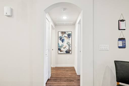 A hallway with a chair and a painting on the wall.