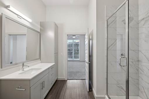 A bathroom with a marble shower and a large mirror.