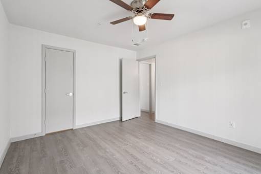 A room with a ceiling fan and wooden flooring.