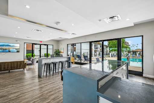 A modern room with a bar and a pool outside.