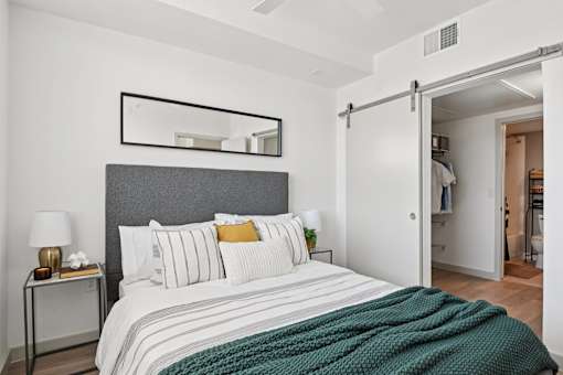 A bedroom with a bed, nightstand, and a mirror above the bed.