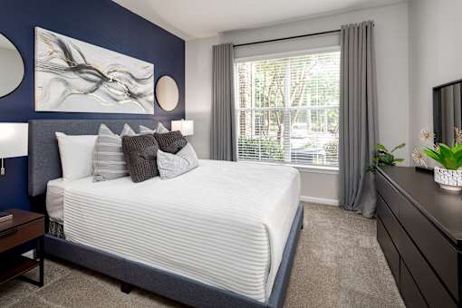 A bedroom with a large bed, a nightstand, and a painting on the wall.