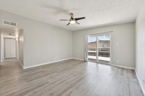 A room with a ceiling fan and sliding glass doors.
