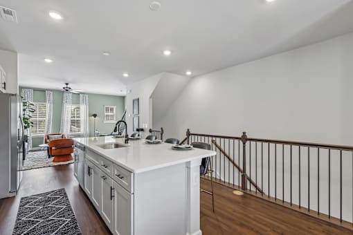 A kitchen with white cabinets and a black and white rug.