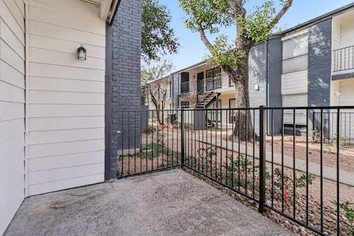 A black metal fence surrounds a concrete patio.