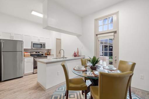 A kitchen with a table set for two with a window in the background.