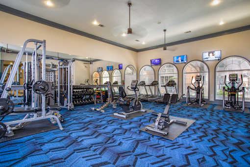 A gym with a variety of equipment including treadmills, weights, and exercise machines.