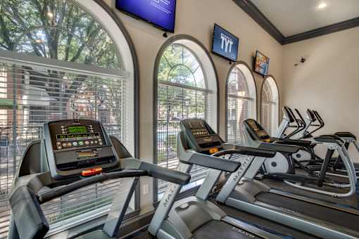 A gym with treadmills and a TV mounted on the wall.