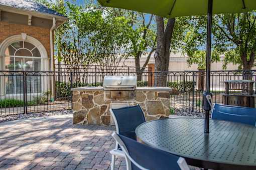 A patio with a table, chairs and a stone pillar.