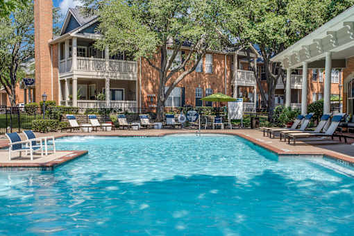 A large swimming pool in front of a building with a balcony.
