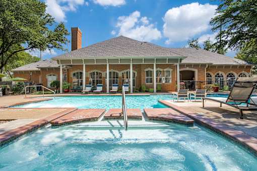 A pool in front of a house with a porch.