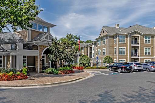 A building with a flag on top and a parking lot in front.