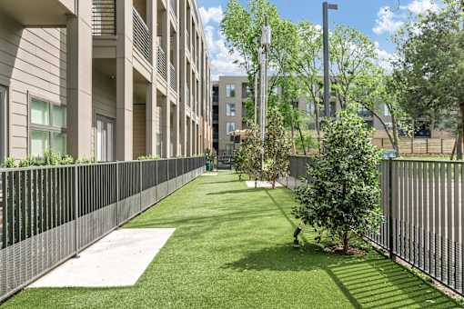 A grassy area in front of a building with a person walking.