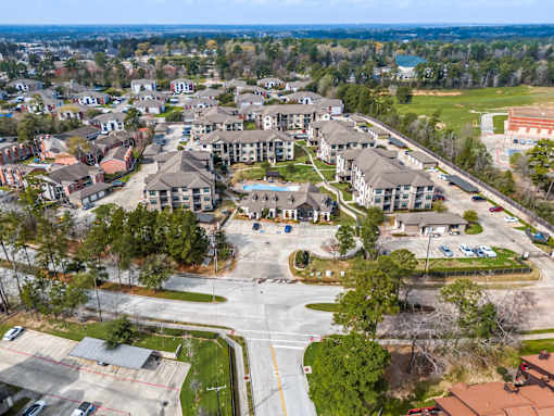 A bird's eye view of a residential area with apartment buildings and a parking lot.
