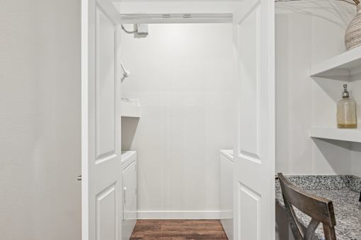 A white hallway with a wooden floor and a chair on the right side.