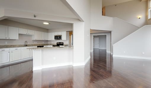 A kitchen with white cabinets and a wooden floor.