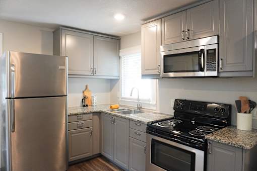 A kitchen with a stainless steel refrigerator, microwave, oven, and other appliances.