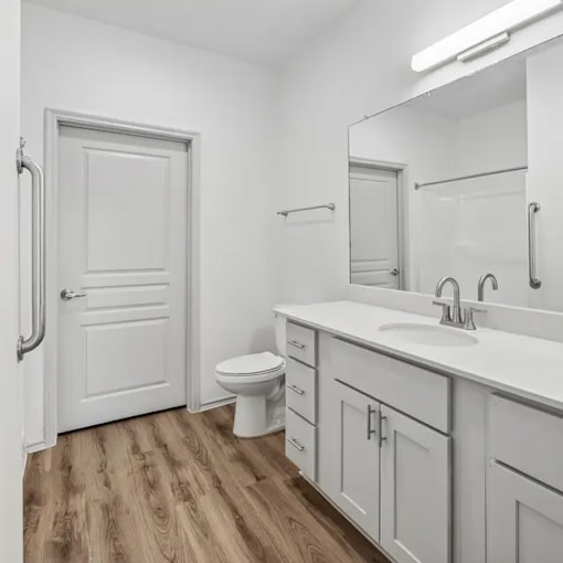 A white bathroom with a toilet, sink, and mirror.
