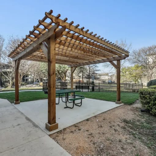 A wooden pergola with a green table underneath it.
