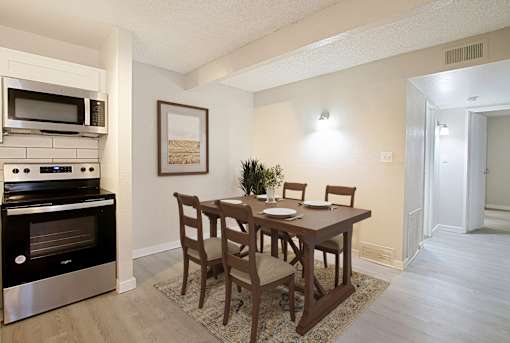 A kitchen with a table and chairs and a fridge.