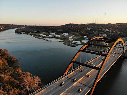 A bridge spans a river with cars driving on it.
