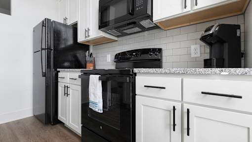 A black refrigerator stands next to a black oven in a kitchen.