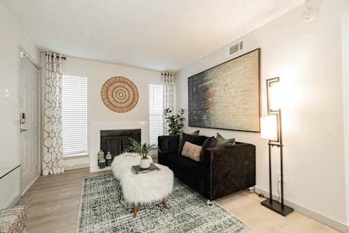 A living room with a fireplace, a couch, a rug, and a painting on the wall.