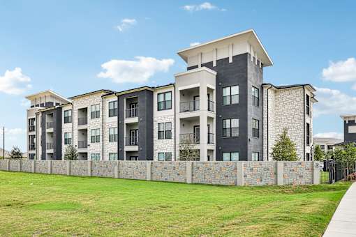 A modern apartment building with a stone wall in front.