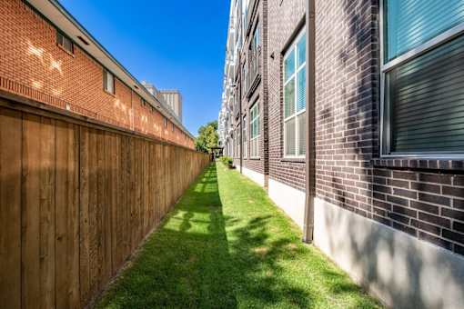 A long, narrow grassy area separates two buildings.