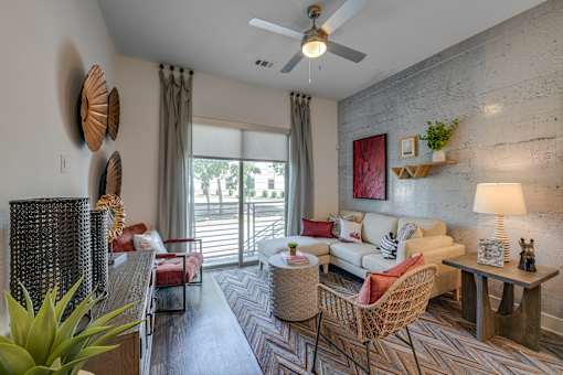 A living room with a sofa, chairs, and a ceiling fan.