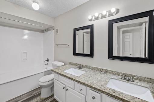 A bathroom with a toilet, sink, and mirror.