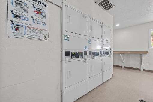 a white kitchen with a row of white refrigerators in it