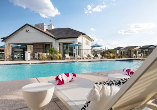 a swimming pool with lounge chairs and a house in the background