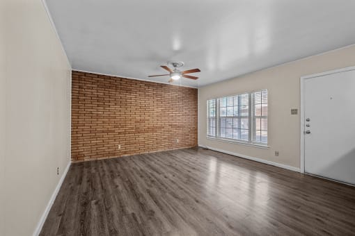 an empty living room with a ceiling fan and a window