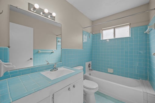a bathroom with blue tile and a white toilet and sink