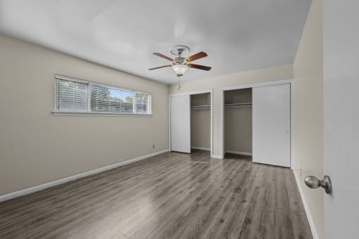 an empty living room with a ceiling fan and a closet