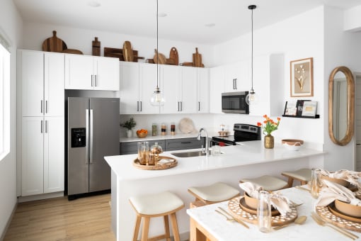 a white kitchen with a large island and a stainless steel refrigerator