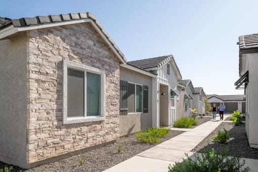 a row of houses with people walking down a sidewalk