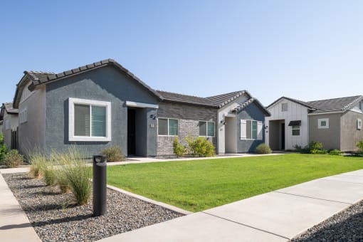 a group of houses in a row on a lawn and a sidewalk