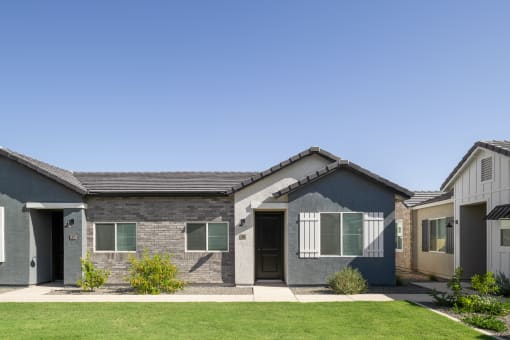 a gray and blue house with a yard and a blue sky