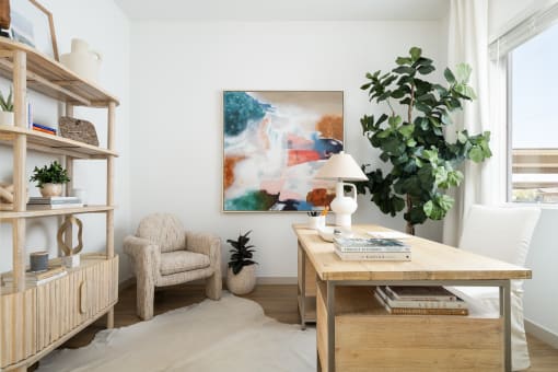 a living room with a desk and a chair and a painting on the wall
