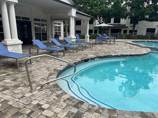 a resort style pool with blue chairs and a building in the background
