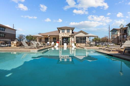 A large swimming pool in front of a building with a fountain in the middle.