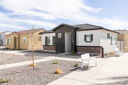 A white bench is in front of a house.