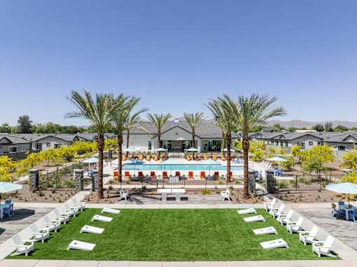 A pool surrounded by palm trees and lounge chairs.
