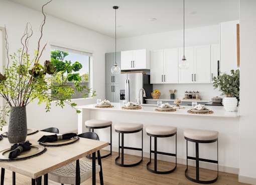 A modern kitchen with a dining table set for two.