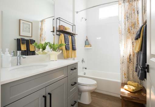 A bathroom with a white toilet, sink, and a shower with a yellow towel.